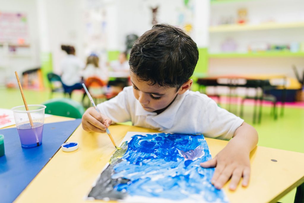 small boy painting a picture during art class