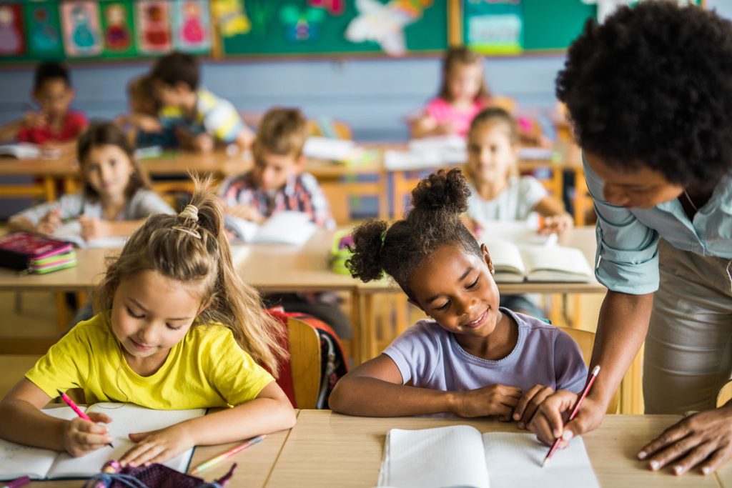 teacher helping young student while they work on their assignments during school