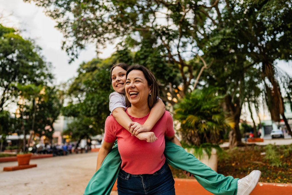 mother smiling with daughter on her back