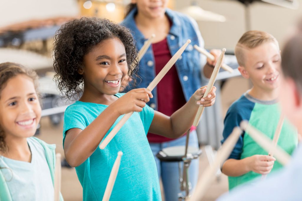 group of students holding drum sticks during music class