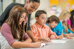 teacher helping middle school students during assignment